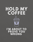 Close-up of asphalt Milk Sandwich T-shirt with white bold text Hold My Coffee, I'm About to Prove You Wrong and a cute steaming coffee cup graphic.