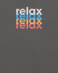 Close-up of a Milk Sandwich t-shirt featuring a stacked and mirrored relax text design in distressed white, blue, orange, and pink colors on asphalt fabric.