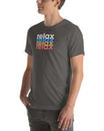 Side view of a man wearing a Milk Sandwich asphalt t-shirt featuring a stacked relax text design in distressed white, blue, orange, and pink colors.
