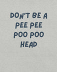 Man wearing light grey “DON’T BE A PEE PEE POO POO HEAD” t-shirt, standing casually with hands by pockets.