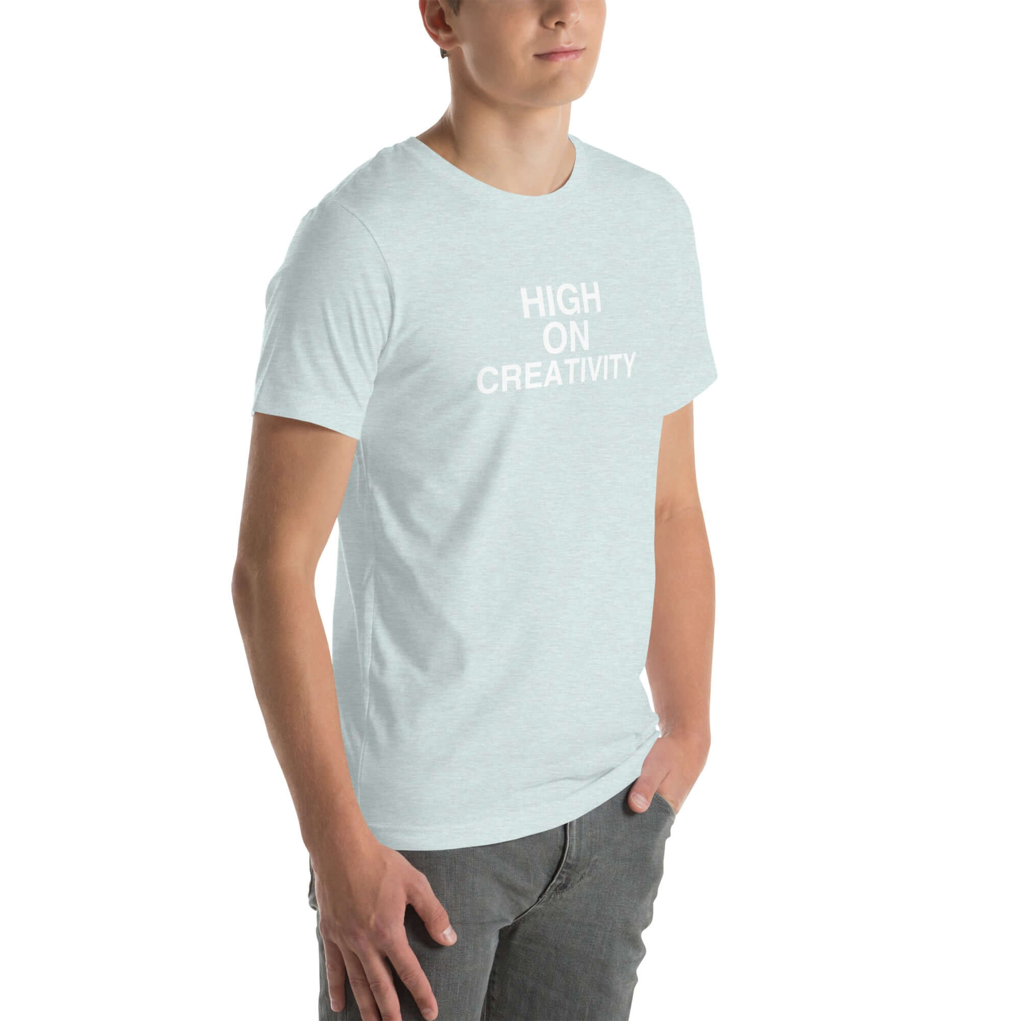 Young man wearing a ice blue t-shirt with white text ‘HIGH ON CREATIVITY’, standing angled to the side with hands in pockets.