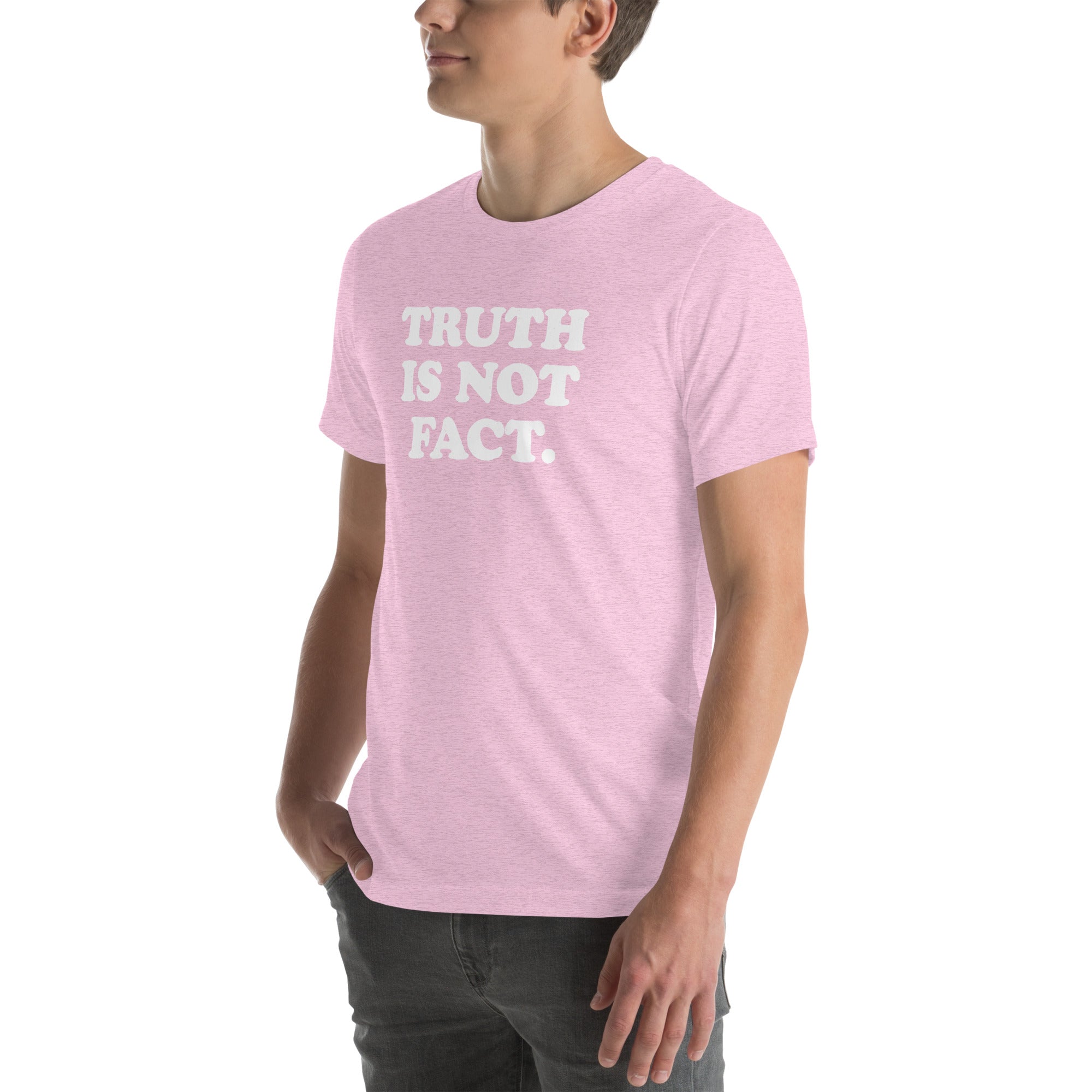 Man wearing a soft pink unisex t-shirt with the phrase &quot;Truth is Not Fact&quot; printed in bold white letters.